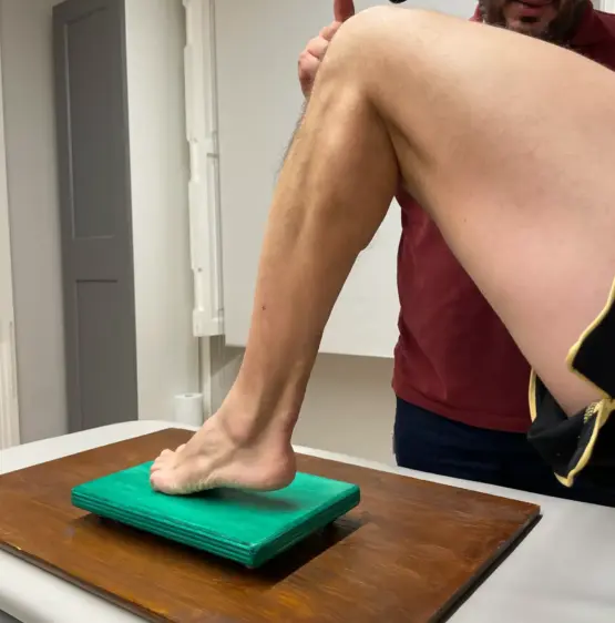 Persona che esegue un esercizio di equilibrio su un materassino di gommapiuma verde, con una gamba sollevata, che mostra un'attenzione impeccabile al posizionamento di gambe e piedi. Questa pratica si allinea perfettamente con 